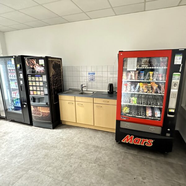 Foto vom Bildungsinstitut am Zentrum Nord. Zu sehen ist der Aufenthaltsraum für Teilnehmende mit Snackautomaten, Getränken und einem Spülbecken.