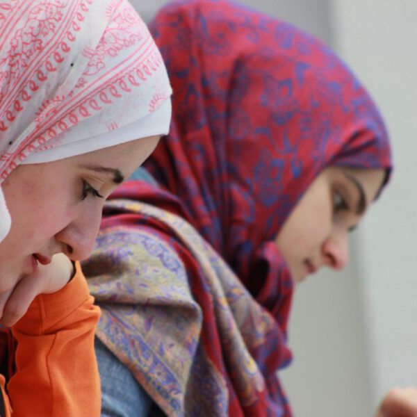 Foto der German Language Academy am Bahnhof. Zu sehen ist eine Lernsituation mit Personen. Beide Frauen tragen ein Kopftuch.